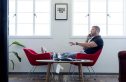 Chase Jarvis sits in a red chair with his feet up talking on his cellphone