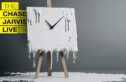 A melting white canvas on a wooden easel, with a clock face placed in the center. The clock hands are black and point outward from the center, but the white material seems to drip and melt off the edges of the canvas, pooling at the base. The background is gray, providing a stark contrast to the melting white substance. To the left of the canvas, yellow and black text reads: "The Chase Jarvis Live Show," with the words stacked vertically in a bold, modern font. The overall composition evokes a surreal and creative aesthetic.